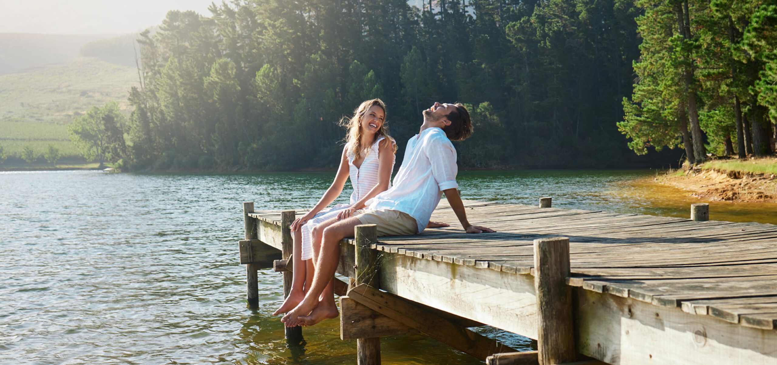 Paar sitzt auf Steg am See und ist glücklich.